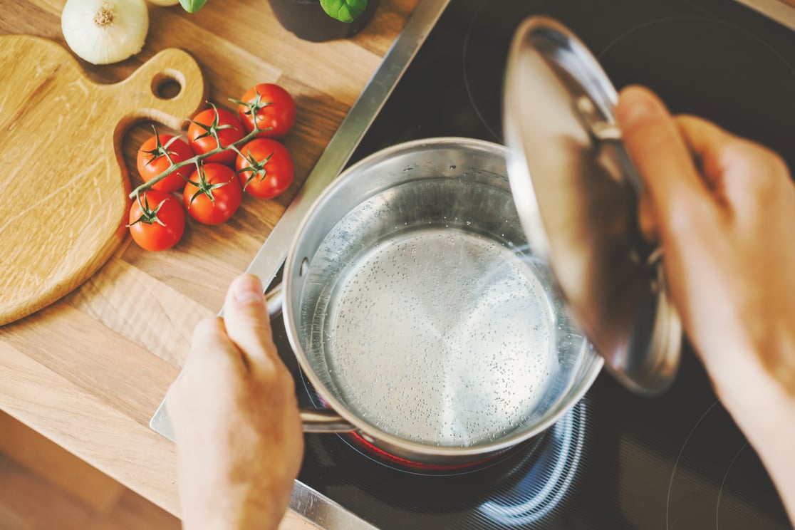 Man checking boiling water in cooking pot.